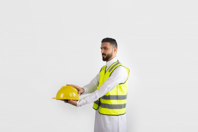 مهندس معماري سعودي محترف يرتدي لباس السلامة  ، مهندس انشاءات خليجي بالثوب السعودي ، خوذة عمل صفراء ، خلفية بيضاء 