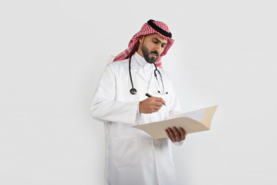 بورتريه رجل طبيب عربي سعودي يتابع ملف تشخيص لحالة المريض ، طبيب خليجي باللباس السعودي ، ملف التشخيص ، خلفية بيضاء