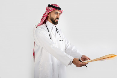 بورتريه رجل طبيب عربي سعودي ، طبيب خليجي باللباس السعودي ، استلام ملف التشخيص  ، خلفية بيضاء