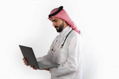 بورتريه رجل طبيب سعودي عربي مسلم ، استخدام الكمبيوتر المحمول ، خلفية بيضاء