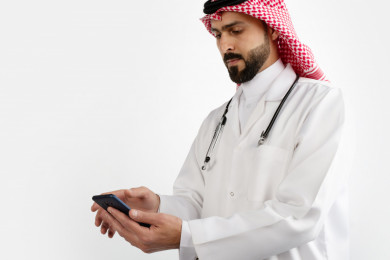 بورتريه رجل طبيب سعودي عربي مسلم ، استخدام الهاتف المحمول ، خلفية بيضاء