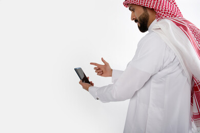 بورتريه رجل سعودي خليجي ، لبس سعودي تقليدي ، استخدام الهاتف المحمول ، خلفية بيضاء