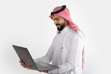 بورتريه رجل سعودي خليجي ، لبس سعودي تقليدي ، استخدام الكمبيوتر المحمول ، خلفية بيضاء