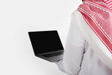 بورتريه رجل سعودي خليجي ، لبس سعودي تقليدي ، استخدام الكمبيوتر المحمول ، خلفية بيضاء