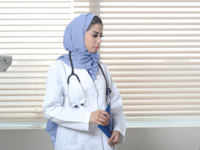 دكتورة سعودية في المكتب  وتمسك في يدها تقرير طبي 
