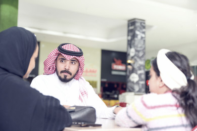 عائلة سعودية سعيدة تجلس في ردهة المطاعم في المول , عائلة سعودية يتحدثان في طاولة المطاعم في المول 