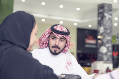 زوج سعودي يتحدث مع زوجتةفي ردهة المطاعم في المول 