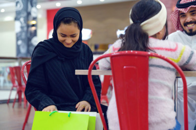 زوجة سعودية  تنظر في أكياس التسوق  في ردهة المطاعم في المول 