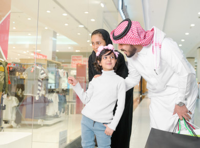 فتاة سعودية صغيرة تشير إلى شيء على واجهة المتجر , عائلة سعودية تنظر إلى واجهة المتجر في المول 