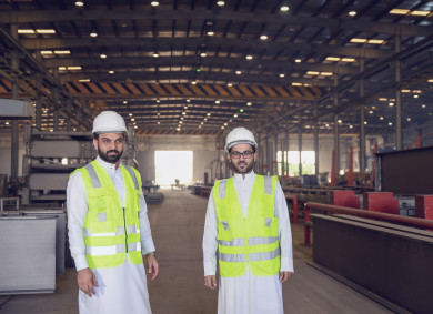مهندسان صناعيان سعوديين شركاء في مصنع الحديد ينظران الي الكاميرا