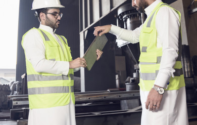 مهندسان صناعيان سعوديين داخل مصنع الحديد ،يشرفان على آلية عمل جهاز صناعة الحديد وكيفيه  تطويره ، ويحمل احدهم  مخطط بيده