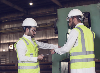 مهندسان صناعيان سعوديين شركاء في مصنع الحديد، يقفان بجانب جهازفي المصنع ، يتناقشان في جودة انتاج المصنع ، الاشراف على انتاجية الحديد و الألمنيوم