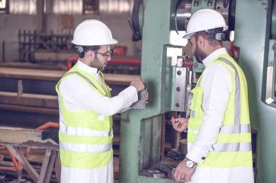 مهندسان صناعيان سعوديين شركاء في مصنع الحديد، يقفان بجانب جهازفي المصنع ، يتناقشان في جودة انتاج المصنع ، الاشراف على انتاجية الحديد و الألمنيوم