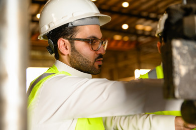 مهندسان صناعيان سعوديين شركاء في مصنع الحديد، يقفان بجانب آلة تصنيع الحديد ، يتناقشان في جودة انتاج المصنع ، الاشراف على انتاجية الحديد و الألمنيوم في المصنع