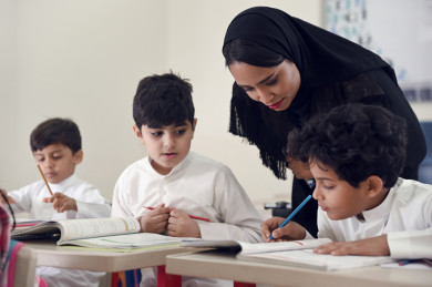 معلمة خليجية تشرف على طالب عن قرب, مدرسة سعودية تنظر إلى كتاب طالب, أستاذة عربية تقرأ حل طالب 