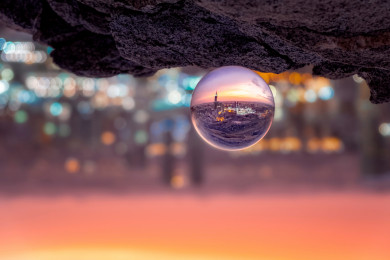 كرة زجاجية تعكس منظر لمكة المكرمة والحرم المكي الشريف، تركيز تصوير تجميعي على الكرة الزجاجية.