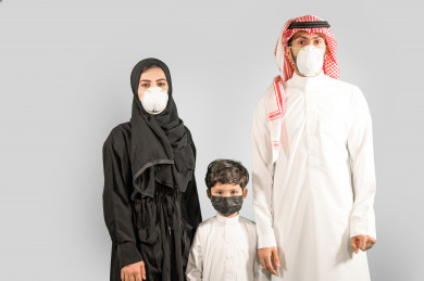 بورتريه عائلة سعودية من أب و ام و الابن و ترتدون الكمامة ، تجنب انتشار العدوى ، الحفاظ على المسافات ، خلفية بيضاء