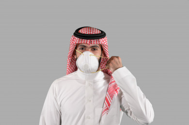 بورتريه لشاب سعودي يقوم بوضع الكمامة ، اتباع اجراءات السلامة بوضع الكمامة بشكل صحيح ، تجنب انتشار العدوى ، خلفية بيضاء