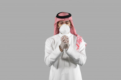 بورتريه لشاب سعودي يقوم بارتداء القفازات ، اتباع اجراءات السلامة بارتداء القفازات ، تجنب انتشار العدوى ، خلفية بيضاء