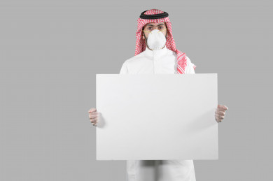 بورتريه لشاب سعودي يضع الكمامة ،  يحمل بيده لوح ابيض فارغ ، اتباع اجراءات السلامة بوضع الكمامة بشكل صحيح ، تجنب انتشار العدوى ، خلفية بيضاء
