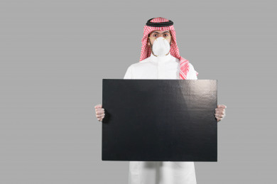 بورتريه لشاب سعودي يضع الكمامة ،  يحمل بيده لوح أسود فارغ ، اتباع اجراءات السلامة بوضع الكمامة بشكل صحيح ، تجنب انتشار العدوى ، خلفية بيضاء