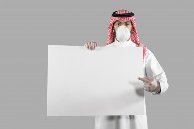 بورتريه لشاب سعودي يضع الكمامة ،  يحمل بيده لوح ابيض فارغ ، اتباع اجراءات السلامة بوضع الكمامة بشكل صحيح ، تجنب انتشار العدوى ، خلفية بيضاء