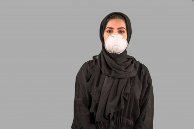بورتريه لفتاه سعودية تقوم بوضع الكمامة ، اتباع اجراءات السلامة بوضع الكمامة بشكل صحيح ، تجنب انتشار العدوى ، خلفية بيضاء
