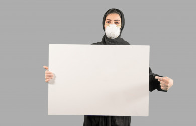 بورتريه لشابة سعودية تضع الكمامة ،  تحمل بيدها لوح ابيض فارغ ، اتباع اجراءات السلامة بوضع الكمامة بشكل صحيح ، تجنب انتشار العدوى ، خلفية بيضاء