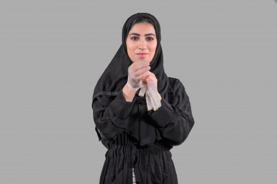 بورتريه لشابة سعودية تقوم بارتداء القفازات ، اتباع اجراءات السلامة بارتداء القفازات ، تجنب انتشار العدوى ، خلفية بيضاء