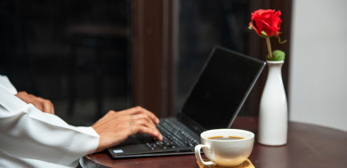 رجل أعمال عربي سعودي سعيد ، يعمل على الكمبيوتر المحمول ، بجانبه  فنجان القهوة ،  متجر القهوه