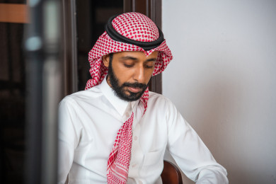  رجل عربي سعودي سعيد  يجلس في المقهى ، طلب القهوه في متجر القهوه