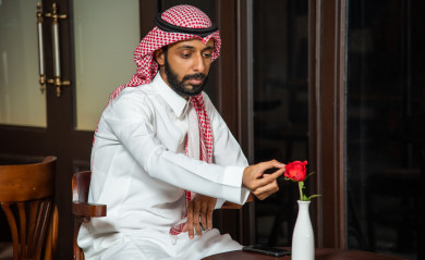  رجل عربي سعودي سعيد  يجلس في المقهى ، طلب القهوه في متجر القهوه