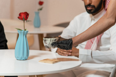 رجل عربي سعودي سعيد  يجلس في المقهى ، يقدم له العامل كوب القهوه  ، طلب القهوه في متجر القهوه