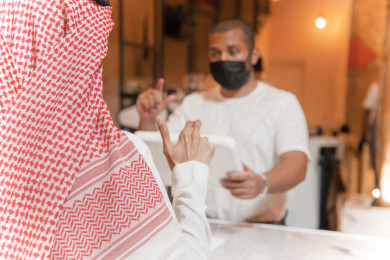 رجل عربي سعودي يفكر باختيار الطلب عند عامل الاستقبال ، طلب القهوه في متجر القهوه