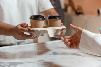 رجل عربي سعودي يحمل اكواب القهوه  بيده ، استلام الطلب ، متجر القهوه