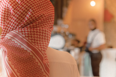 رجل عربي سعودي ينتظر طلبه عند الاستقبال ، طلب القهوه في متجر القهوه